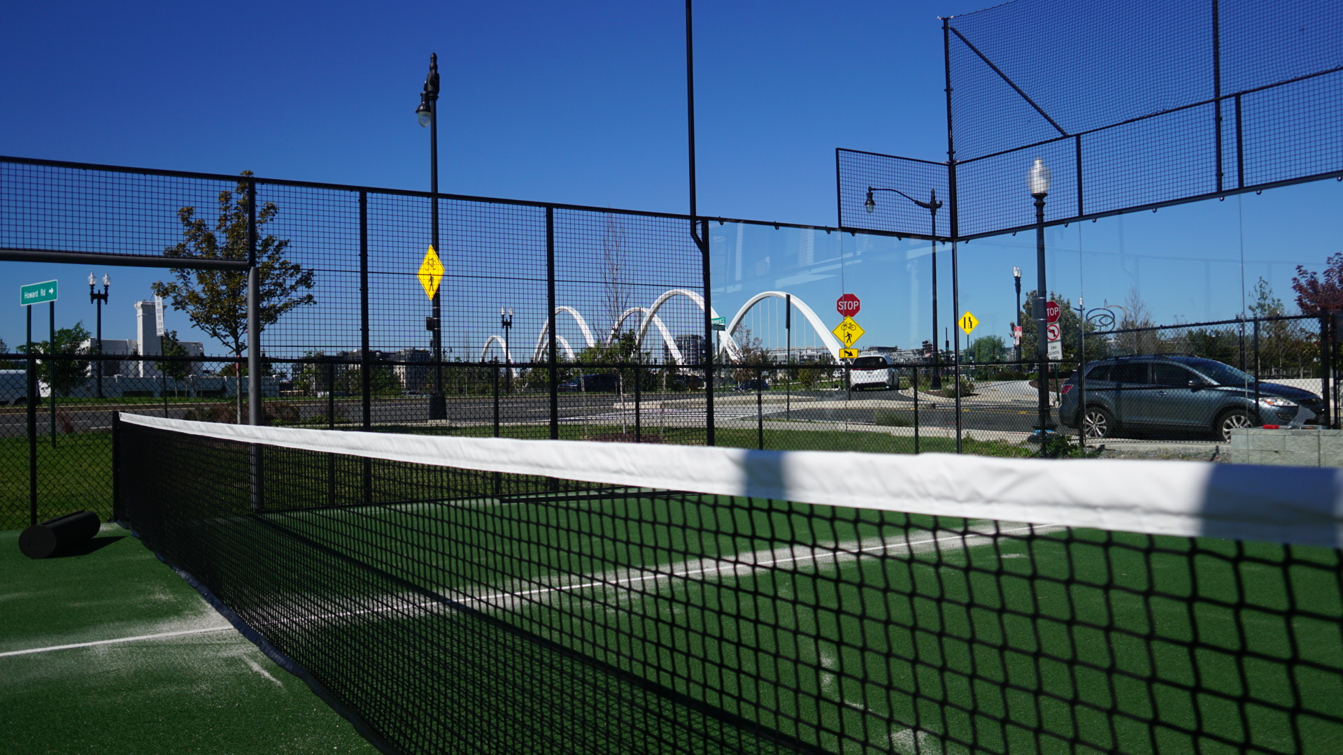 The white arches of the Frederick Douglass Memorial Bridge seen through the court fence